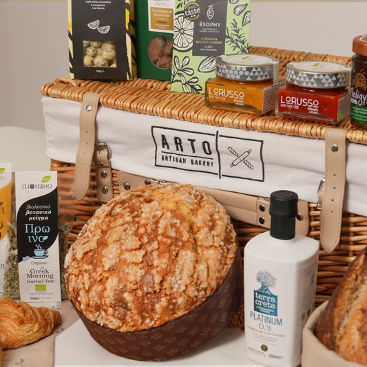 Wicker basket with bread, pastries, and various items on a white surface